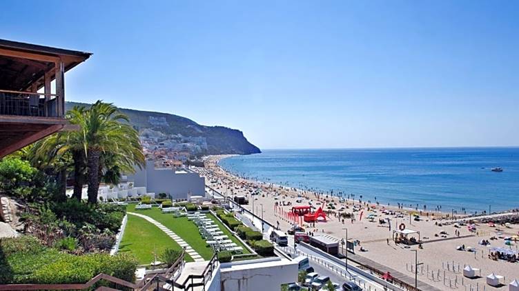 A beach with a body of water and buildings

Description automatically generated